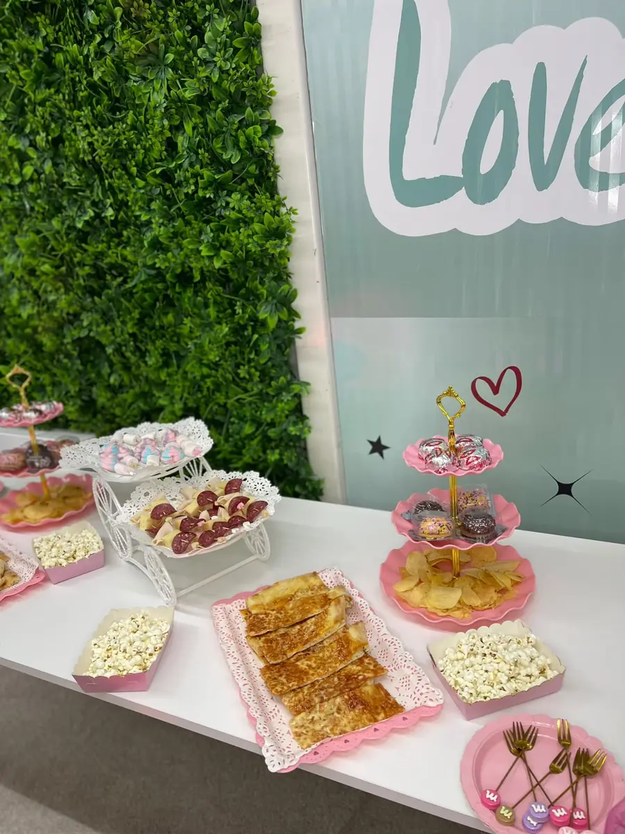 The snack table with popcorn, sweets and pink tiered stands